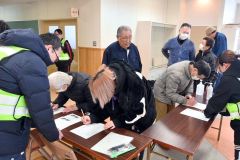 避難所で「避難者受付管理簿」に必要事項を書き込む住民ら