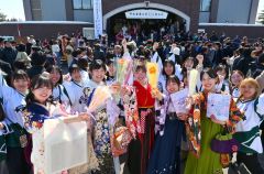 女子アイスホッケー部の後輩から花束を受け取り「ゴール」のポーズを見せる卒業生（１９日、午前１１時３５分ごろ。金野和彦撮影）
