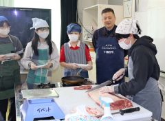 寺原工場長（右から２人目）の指導で肉を切る児童