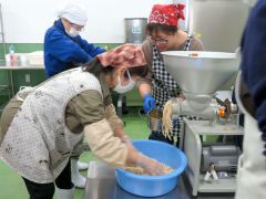 参加者に大豆の混ぜ方のこつを伝える鎌田さん（左）