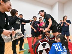 「この調子で頑張って―」。佐藤選手（左）の応援を背にワットバイクをこぐスケート部員
