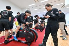 ワットバイクリレーで激走する梅川選手（左）と速度計を確かめる佐藤選手（右）