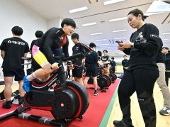 ワットバイクリレーで激走する梅川選手（左）と速度計を確かめる佐藤選手（右）