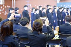 卒業を迎えた我が子の姿をスマホで撮影する保護者たち（更別、長尾悦郎通信員撮影）
