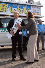 妻の光子さんからたすきをかけてもらう小野氏（２５日午前９時ごろ、須貝拓也撮影）