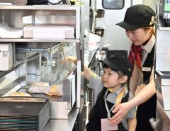 一緒に作ったハンバーガーを店頭に運ぶ子どもと小牟禮さん