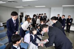 ８人の新１年生に記念品を渡している各社代表ら