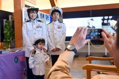 自衛隊の制服を着用し、記念撮影してもらう親子連れ