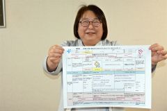 法人独自で制作した妊娠から復職までの流れが一覧で分かるシートを手にする開西病院の職員