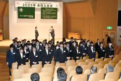 新入社員を代表して決意表明を述べる二瓶誠さん（後方右）と関係者の前に整列する新入社員たち（１日、午前１０時４０分ごろ、とかちプラザで。金野和彦撮影）