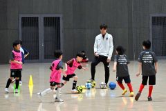 子どもたちにサッカーを指導し、笑顔を見せる松島仁さん(右から3人目)
