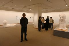 さまざまな彫刻が並ぶ会場と板東さん（左）