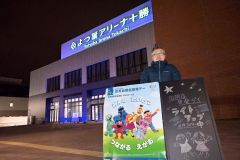 青く照らされたよつ葉アリーナの前で啓発する新津会長