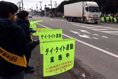 「旗の波作戦」で安全運転を呼び掛ける参加者ら