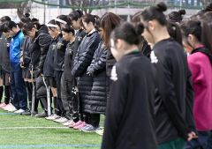 西村さんをしのび黙とうをささげる帯北ロッカフォルテ十勝合同チーム（正面）ら参加選手たち（６日正午ごろ、帯広北高校グラウンドで。塩原真撮影）