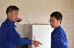 高齢者宅に見守りセンサーを設置するテクノスジャパンの牛谷相談役（左）ら