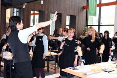 明るい実習室で講師（左）からハサミの持ち方を学ぶ学生