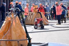 ホースをつないで水源から散布装置のついたバケットへ水を注ぐ訓練参加者（須貝拓也撮影）