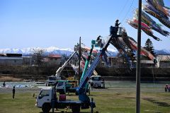高所作業車を使い川の上を渡されるこいのぼり(18日午前10時半ごろ、須貝拓也撮影)