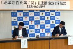 「地域活性化等に関する連携協定書」に署名する（左から）米田社長、田中町長