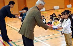 ランチョンマット等を受け取る代表児童