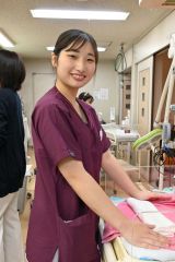 新生児をケアする台の前で笑顔を見せる山口さん