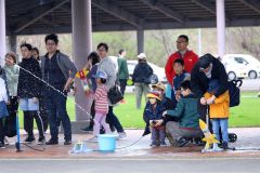 ペットボトルロケットで遊ぶ親子連れら。遠くまで飛ばそうと、必死に空気を入れていた（５日午前１１時２０分ごろ、助川かおる通信員撮影）