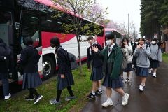 見送りにきた保護者らに手を振りながらバスに乗り込む帯広第四中の生徒（７日午前７時半ごろ、須貝拓也撮影）