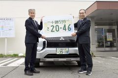 十勝ナンバーの特大プレートを手にする辻榮支局長（左）と竹中会長（午前９時半ごろ、須貝拓也撮影）