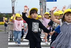 上に大きく手を上げ、ドライバーに合図を送る園児たち