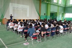 体育館で講義を受ける生徒ら