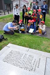 旧帯広小学校跡地（現帯広中央公園）で、大和田学芸員（左手前）の説明を受ける児童ら（金野和彦撮影）