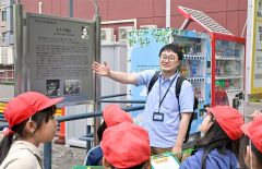 看板を見ながら歴史を説明する大和田学芸員（金野和彦撮影）