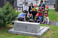 旧帯広小学校跡地（現帯広中央公園）で、大和田学芸員（左手前）の説明を受ける児童ら（金野和彦撮影）