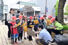 大和田学芸員（右手前）から旧藤丸の当時のにぎわいの動画を見る児童（金野和彦撮影）