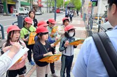 まちなかで看、板を見ながら大和田学芸員（右手前）の説明を受ける児童（金野和彦撮影）
