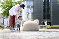 噴水で水遊びを楽しむ親子（２９日午前１０時ごろ、帯広市の中央公園で。須貝拓也撮影）