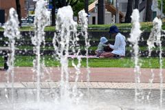 木陰でくつろぐ親子（２９日午前１０時ごろ、帯広市の中央公園で。須貝拓也撮影）