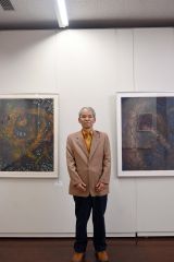 本人の力作の前で来場を呼び掛ける匂坂代表