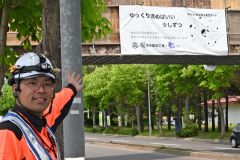 交通安全のメッセージが入ったアートを紹介する樋渡常務取締役