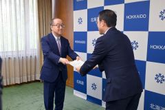 報告書を手渡す丸谷代表幹事（左）