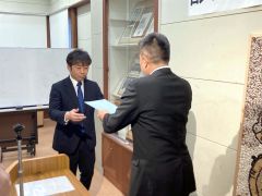 池田会長（右）から出馬要請書を受け取る岡崎氏