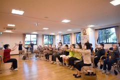 体の体操などでウオーミングアップする参観者ら