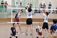 【男子予選グループ戦・帯三条―旭川実】第２セット、スパイクを打つ帯三条の吉田匠之介（白あずき色ユニホーム、左）＝金野和彦撮影