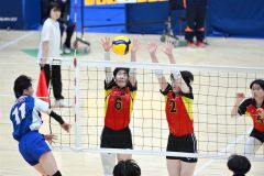 【女子予選グループ・帯南商―東海大札幌】第１セット、ブロックに飛ぶ帯南商の唐﨑愛華（赤色ユニホーム、左）と富田凛（同、右）＝金野和彦撮影