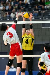 【女子３位決定戦・札幌山の手―旭川志峯】第２セット、ブロックに飛ぶ札幌山の手黒井沙梨（黄色ユニホーム、豊頃中出）＝金野和彦撮影