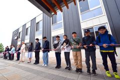 施設のオープンを祝い、テープカットを行う関係者と地元住民（１５日、午前１０時２０分ごろ。ＪＲ新得駅前で。金野和彦撮影）