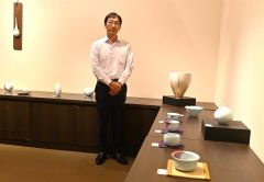 青瓷紅斑茶碗などの新作が並ぶ会場と三上さん