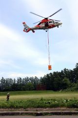 バケットをつるして高く飛び立つヘリコプター