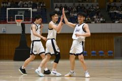 【男子決勝リーグ・白樺学園―旭川志峯】第２クオーター、白樺学園の齊藤煌空（中央）が３ポイントシュートを決め、中西英大とタッチを交わす（金野和彦撮影）